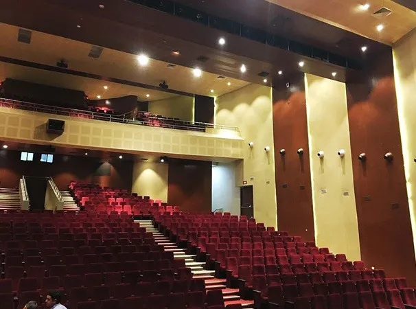 View from the balcony over rows of red auditorium seats and panelled side walls