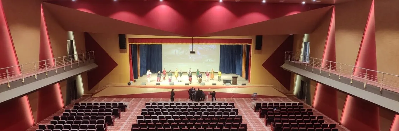 A large auditorium with red seating, a red ceiling and a lit stage